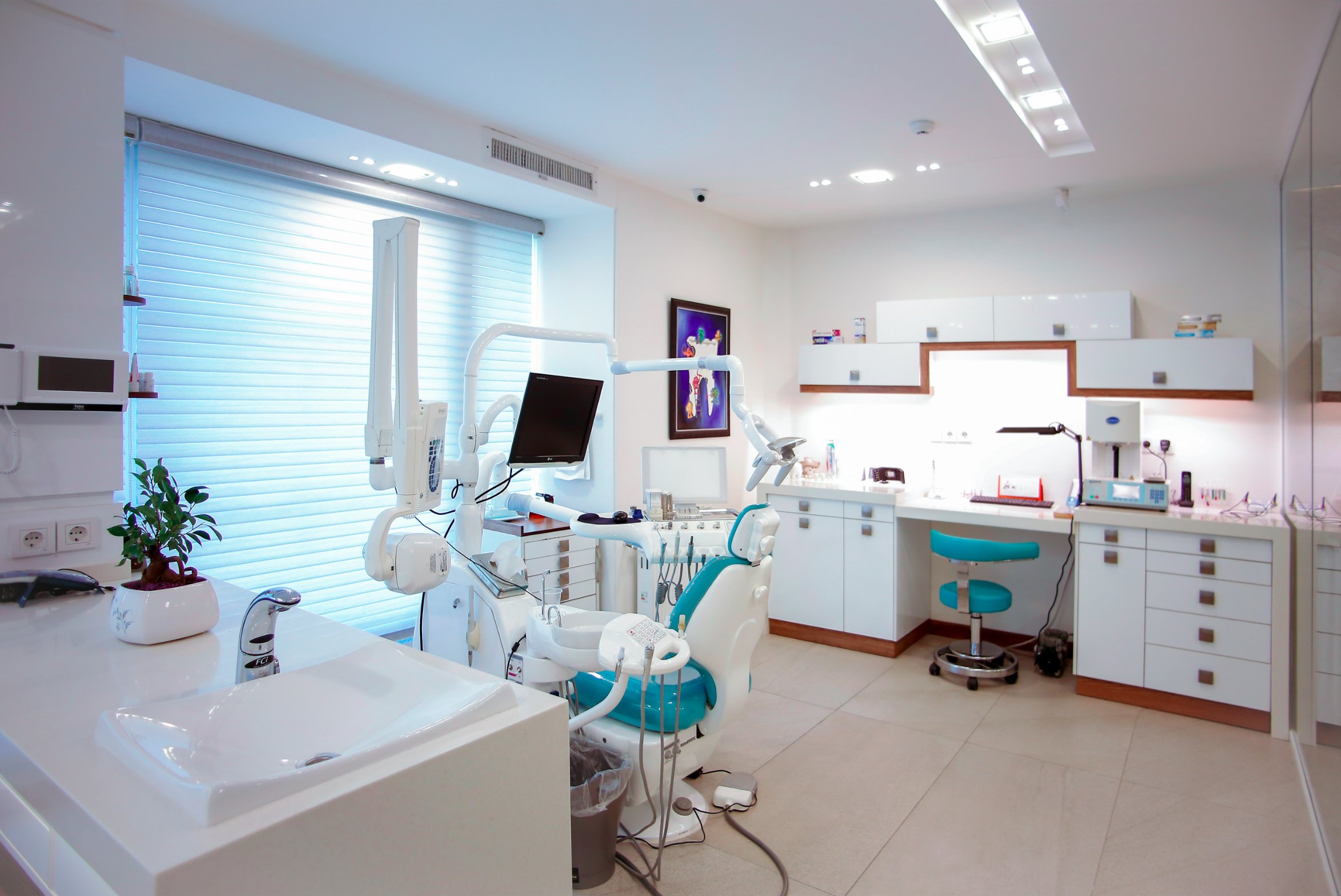 A modern dental operatory with a teal dental chair and treatment equipment