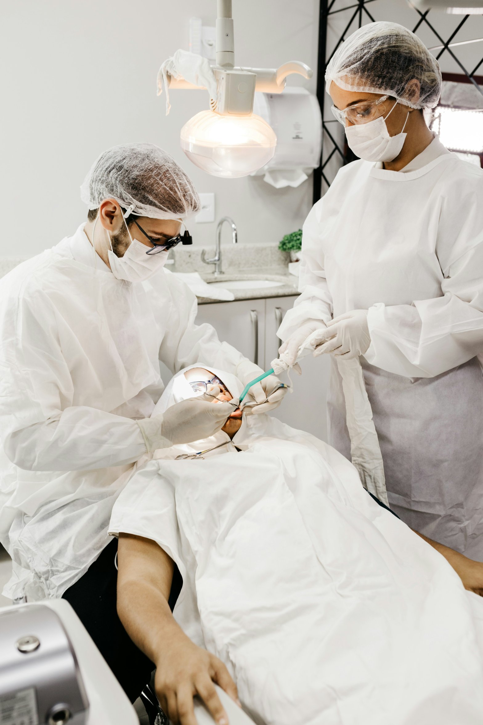 A dentist and dental assistant in protective gear treating a patient